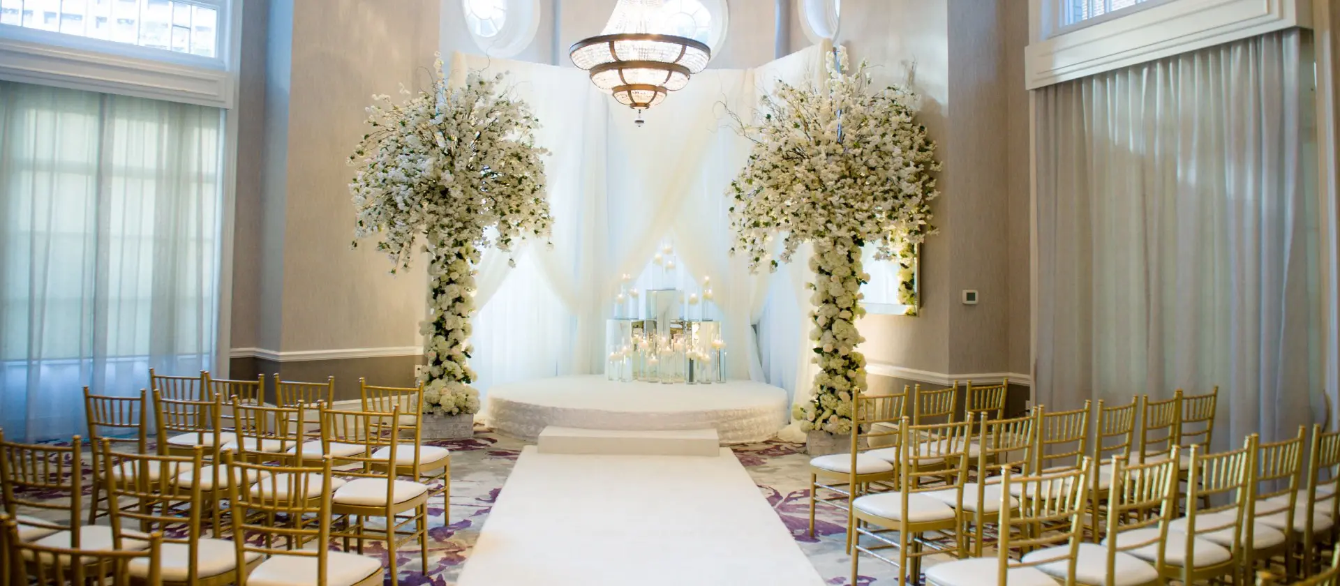 A wedding ceremony with white flowers and gold chairs.