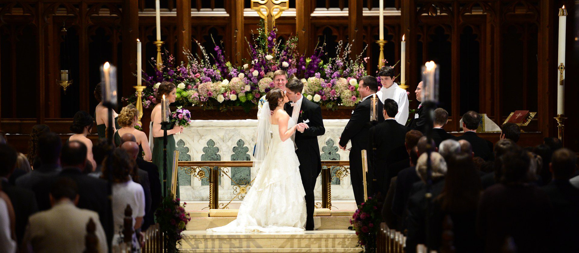 A bride and groom are kissing in front of the altar.