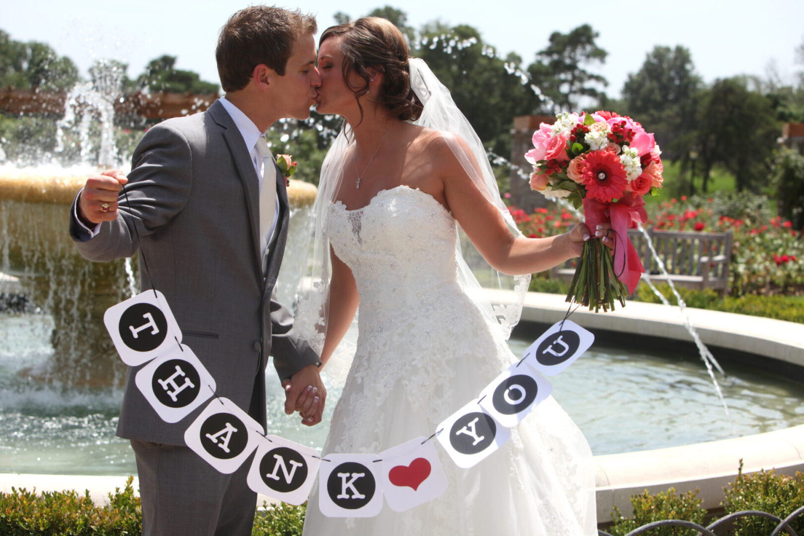 A bride and groom kissing in front of a fountain.