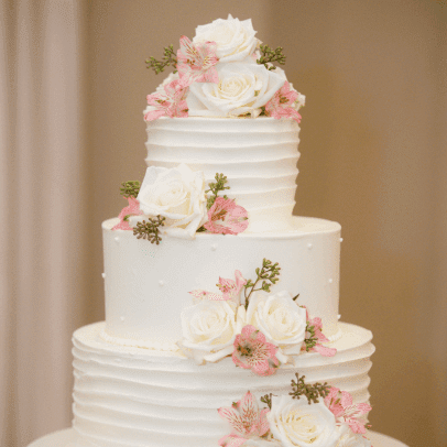 A three tiered white cake with pink flowers on top.