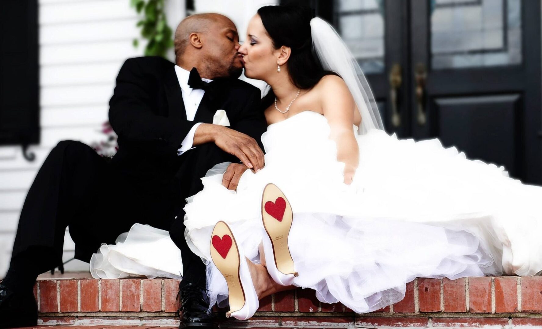 A man and woman kissing on the steps of their wedding.