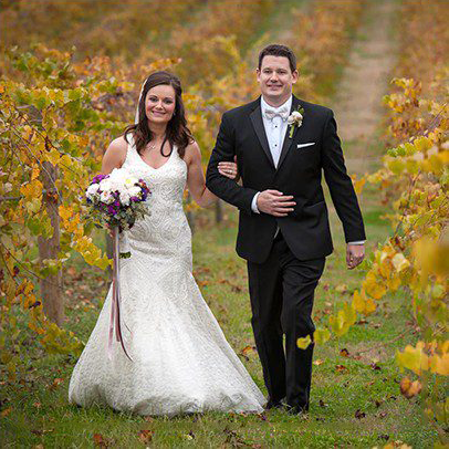 A bride and groom walking through the vines